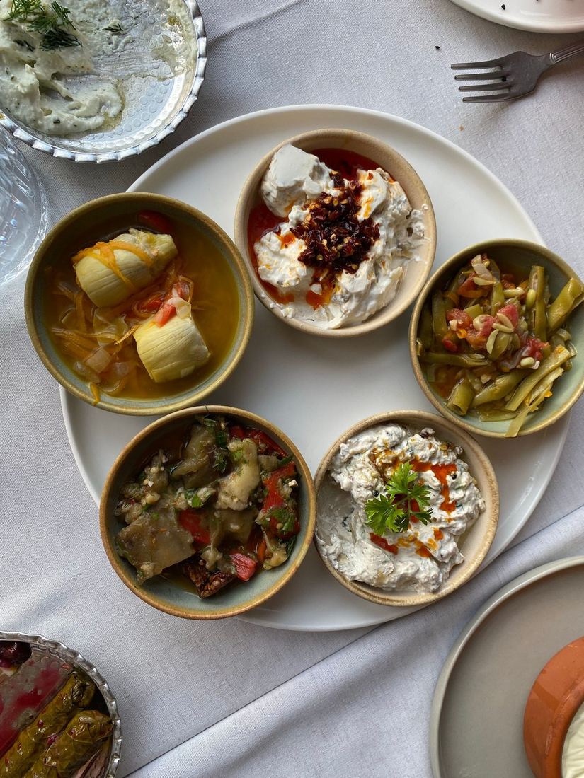 A spread of mezze dishes on a white cloth seen from above